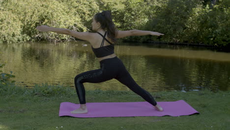 young woman doing warrior poses near pond