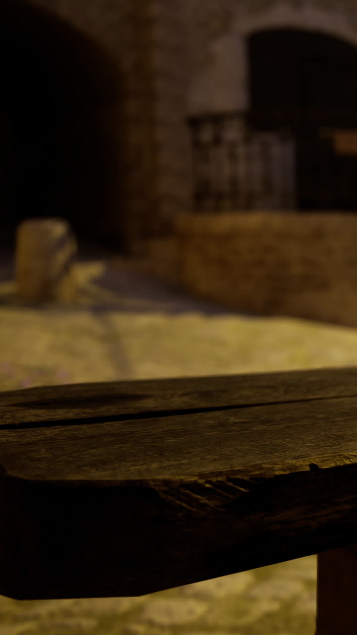Un tavolo in legno in un'area esterna scarsamente illuminata vicino a un muro di pietra di notte.