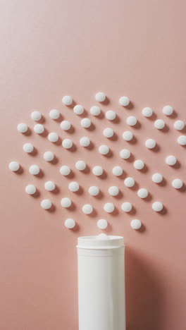 vídeo vertical de caja de pastillas abierta y pastillas blancas sobre fondo rosa con espacio para copiar