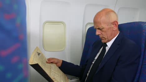 a mature businessman reading a newspaper on an airliner airplane