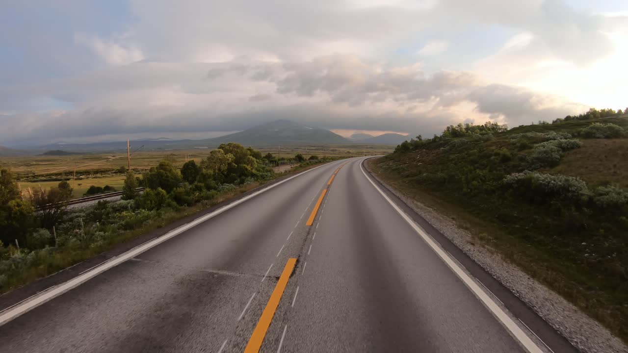 Dirigindo um carro em uma estrada na Noruega ao amanhecer