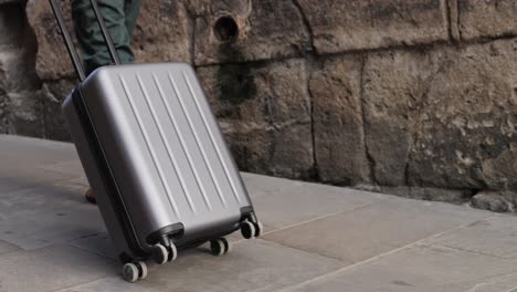 Person walking with a silver suitcase on a city street