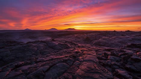 a breathtaking transformation of the landscape at dusk: witness the stunning color palette of a sunset over rugged terrain and volcanic formation