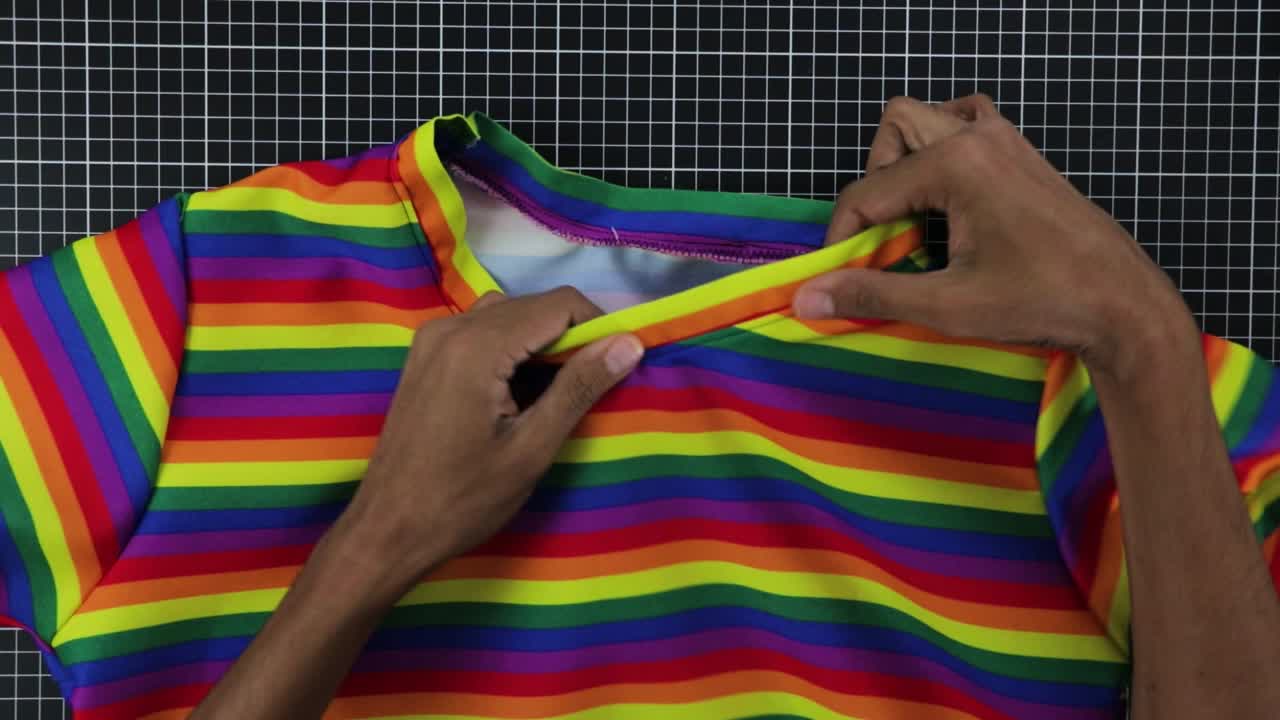 라틴계 남자가 무지개색 티셔츠를 디자인하고 있습니다.