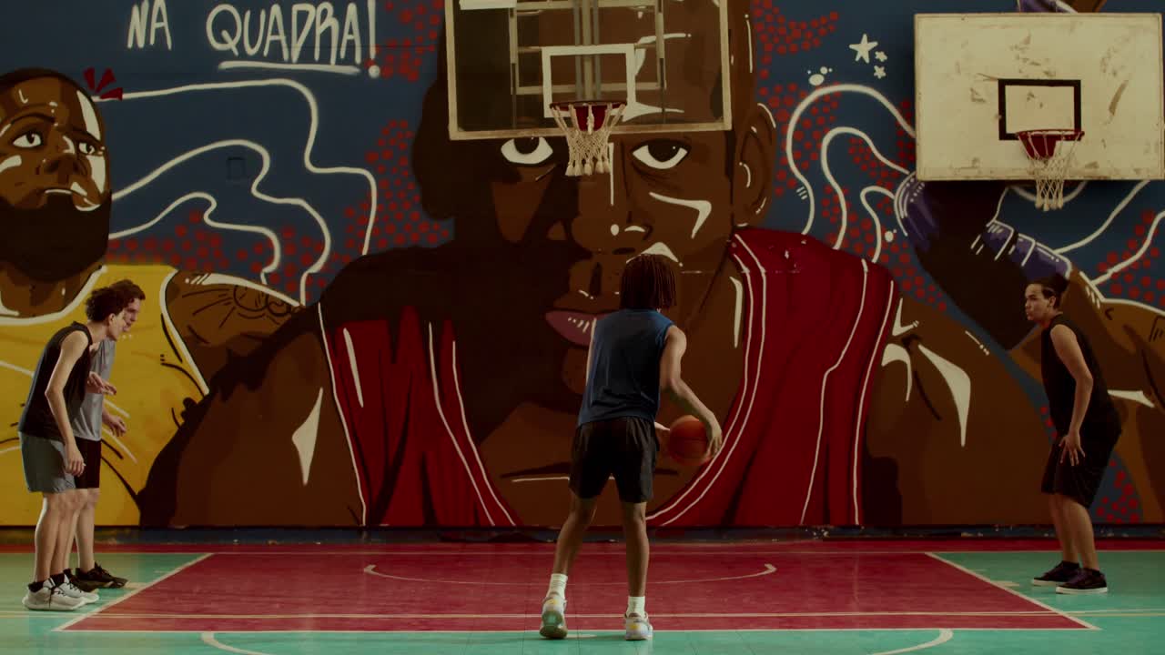 Youth playing basketball on an indoor court with a vibrant mural