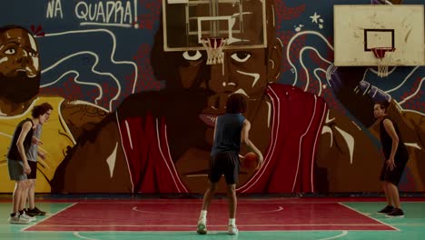youth playing basketball on an indoor court with a vibrant mural