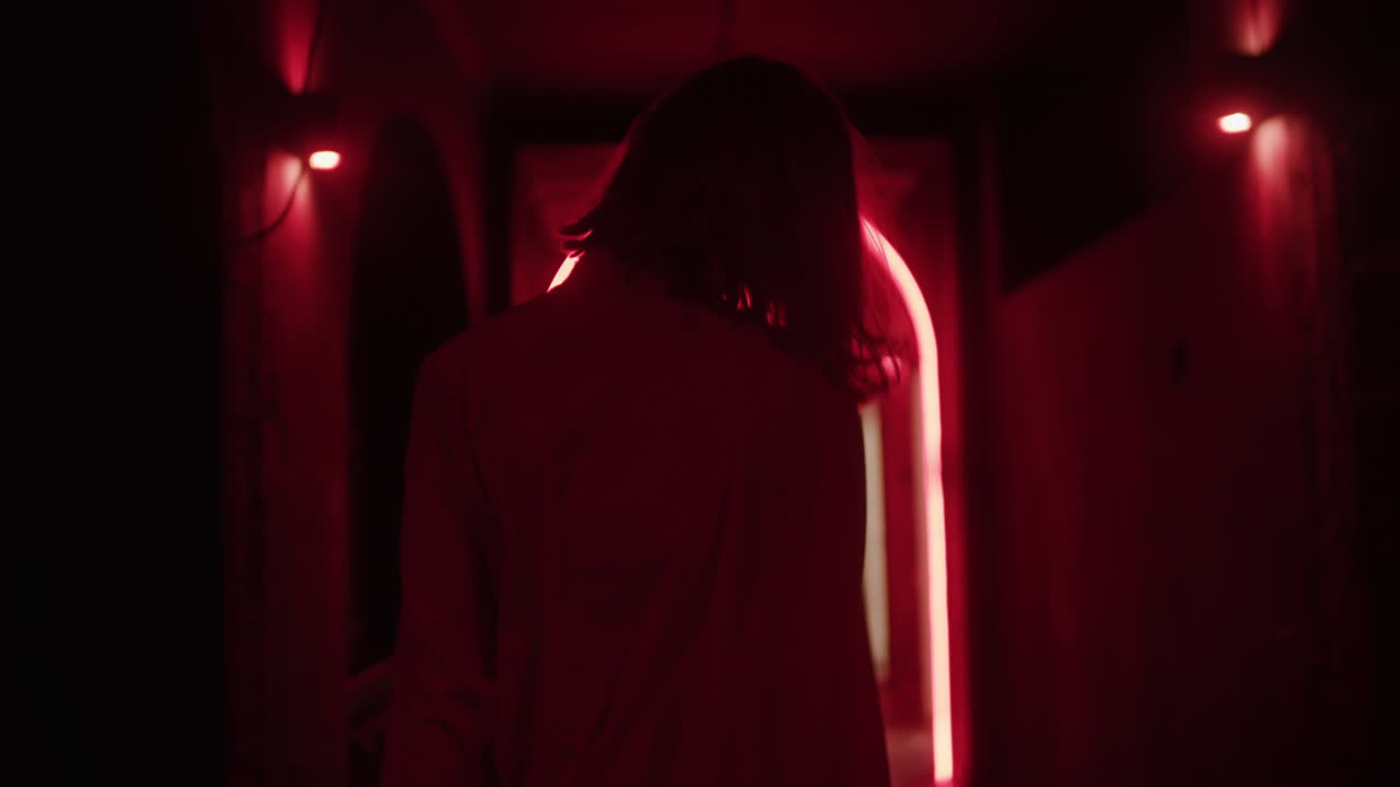Donna che cammina attraverso un arco illuminato di rosso neon