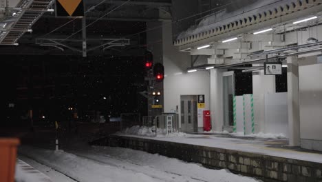 snow falling over aomori train station at night, heavy winter storm in japan