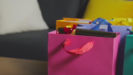 cerca de regalos envueltos en bolsas de colores con etiqueta en la mesa en el salón en casa 4