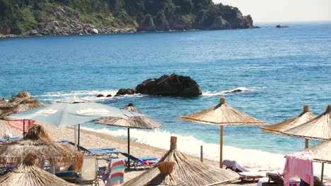 View-of-straw-umbrellas-and-sunbeds-on-the-shore-of-a-beautiful-Albanian-beach