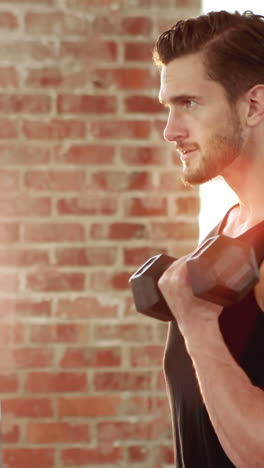 fit man lifting heavy black dumbbell