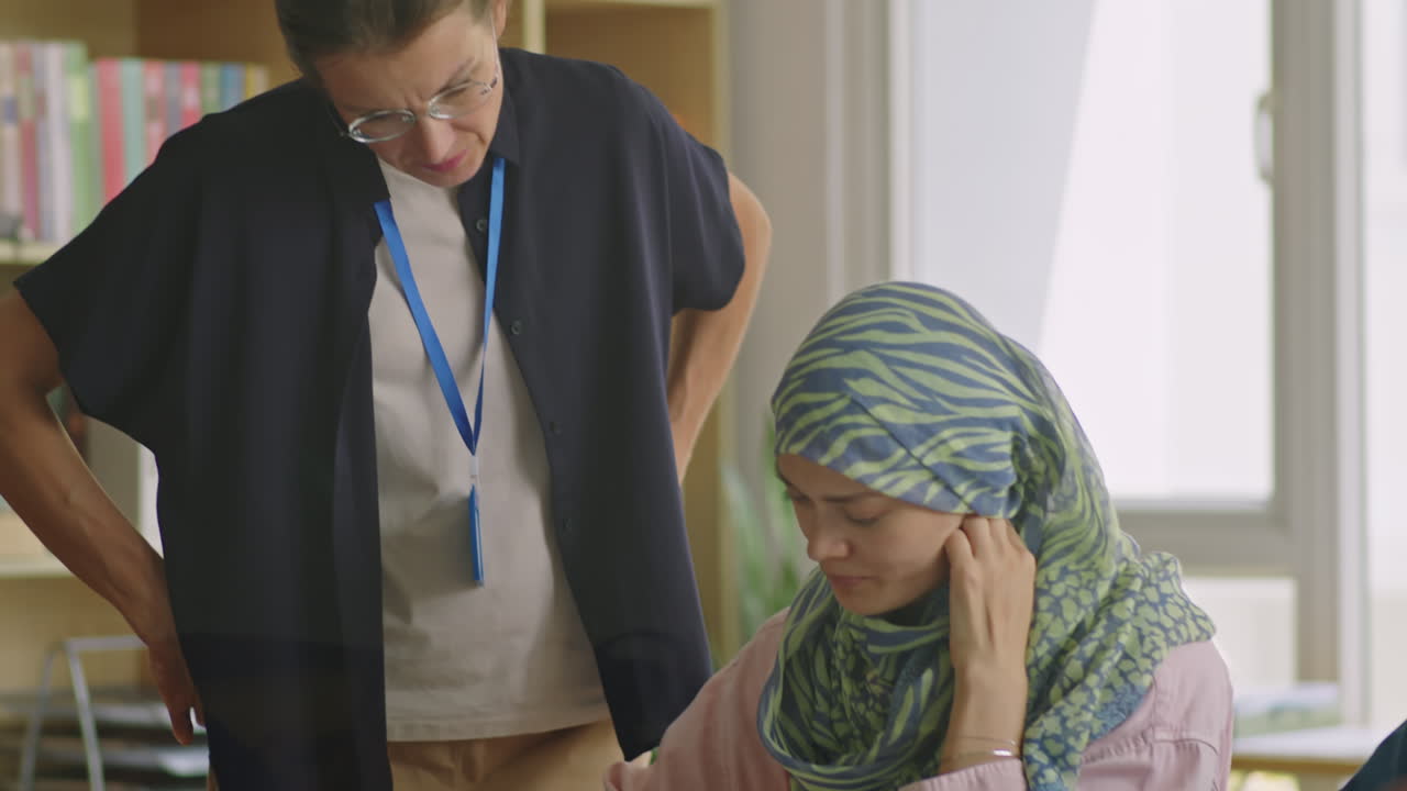 Female Student in Hijab Doing Assignment with Help of Teacher