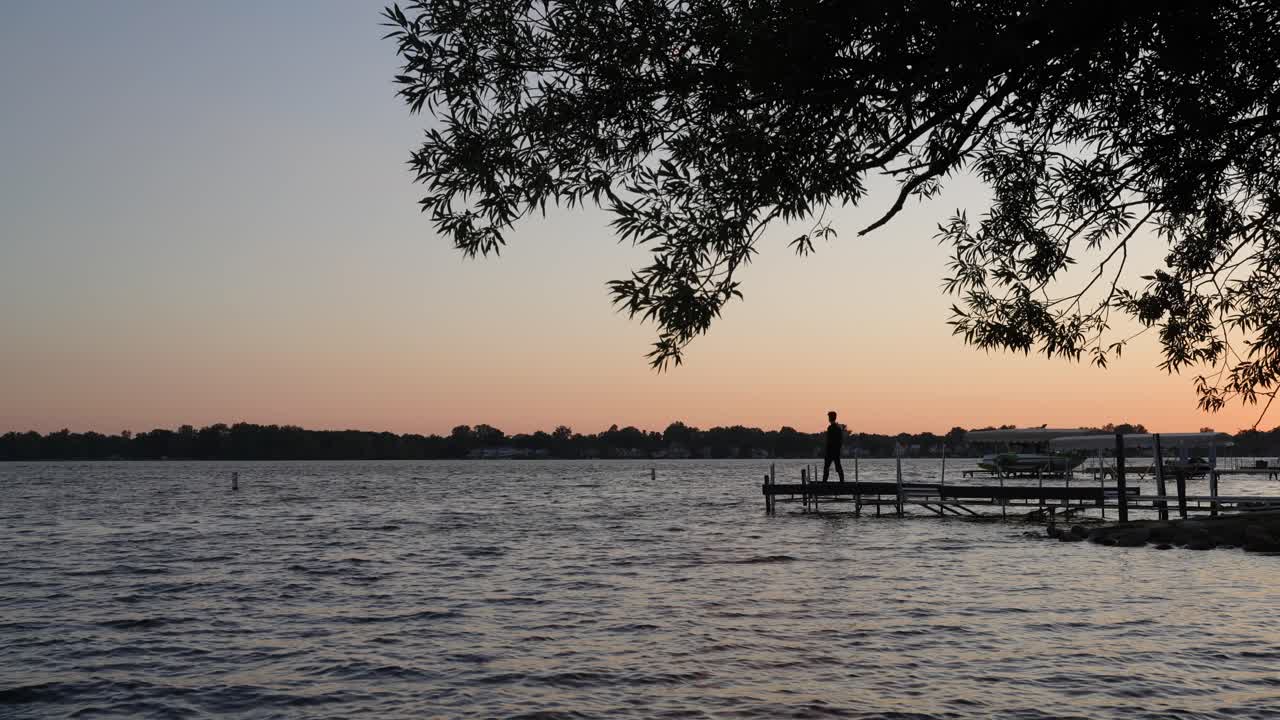A silhouette of a man looking at a lake during sunset in Michigan