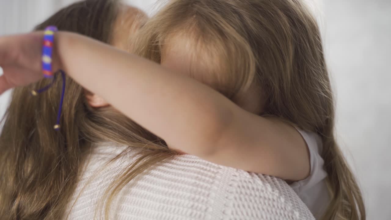 The blonde girl in her mother's arms is very happy.