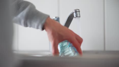 hombre llenando su vaso con agua del grifo y luego vertiéndola