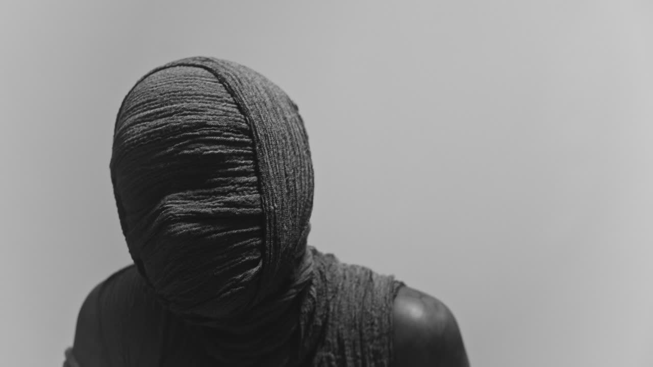 A mummy of a woman on a white backdrop rises her head