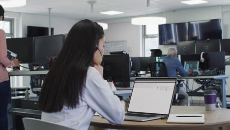 Asian woman sitting at desk watching coding data processing on laptop screen