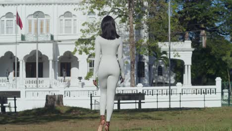 In-a-Caribbean-city,-castles-loom-in-the-background-behind-a-young-girl-in-a-white-bodysuit