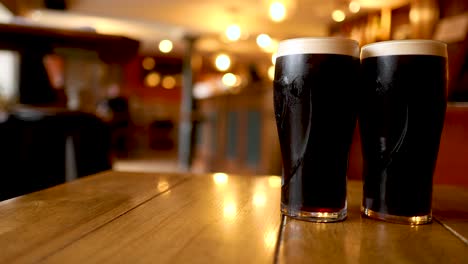 two pints of stout on a wooden table