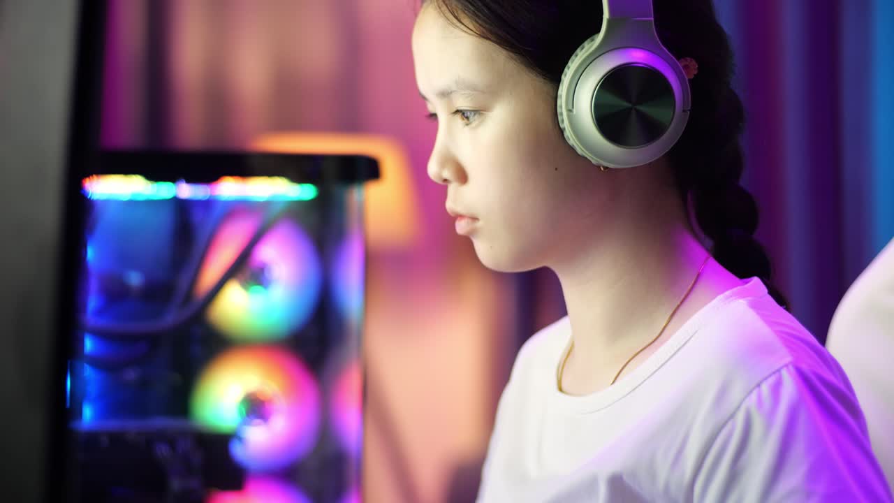 흥분한 아시아 십대 소녀 게이머가 컴퓨터에서 비디오 게임을 하면서 승리를 축하합니다.