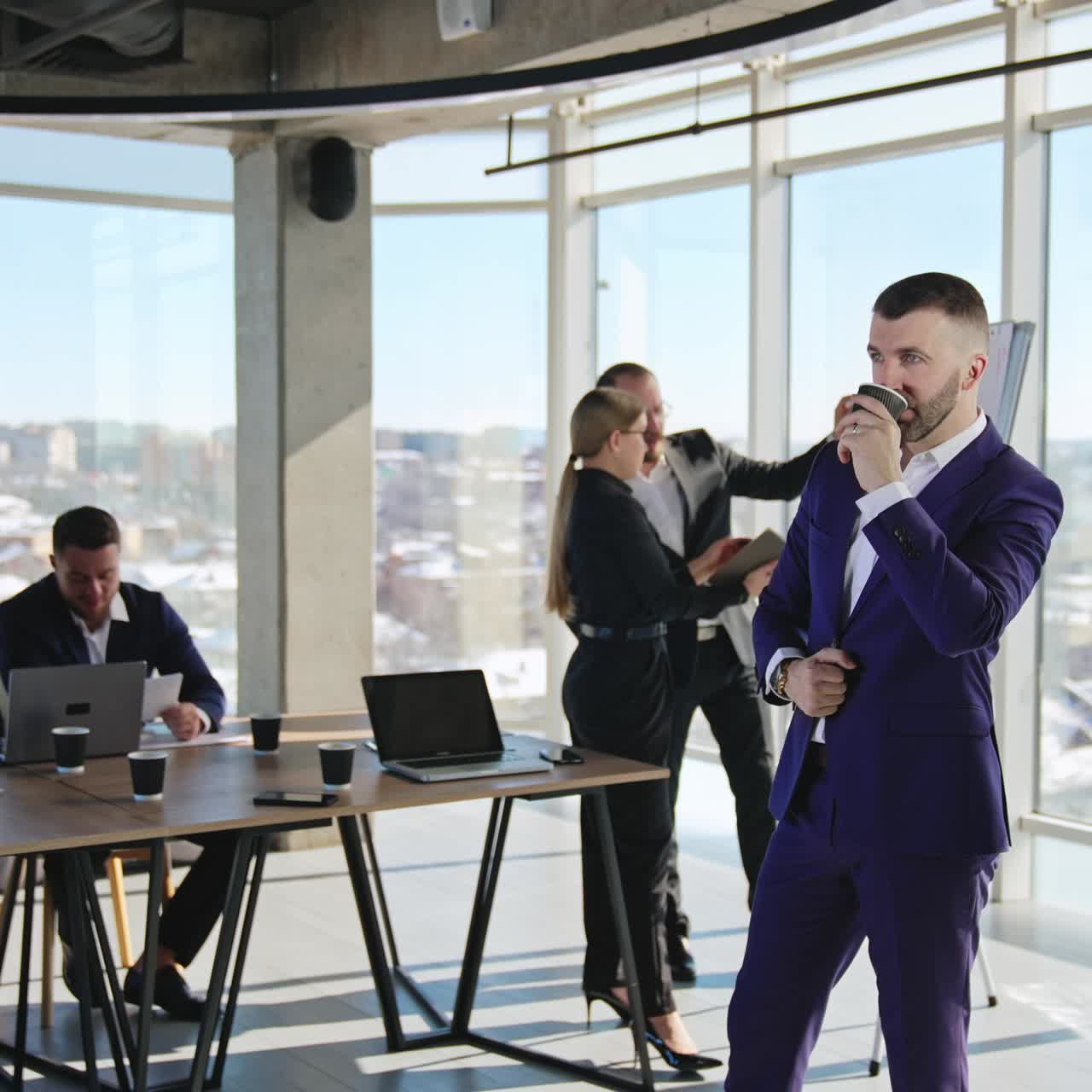 Middle-aged businessman standing in office, drinking coffee and ...