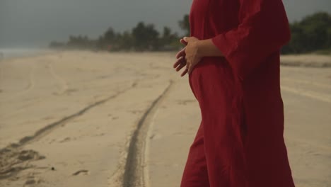 Ein-Mädchen-In-Einem-Roten-Kleid-Steht-An-Einem-Strand-Und-Steckt-An-Einem-Sonnigen-Tag-Die-Hände-In-Die-Taschen-Ihres-Roten-Kleides