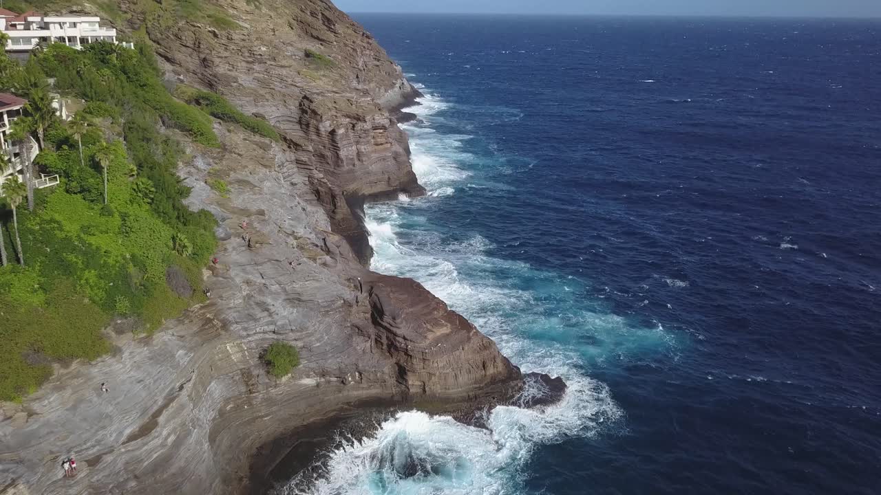 revelan una toma de vegetación brillante y olas masivas rompiendo en una cueva tropical en honolulu hawaii - revelación de retroceso aéreo