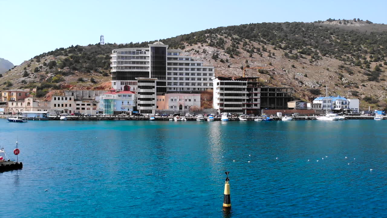 Coastal Cityscape with Buildings, Mountains, and Boats