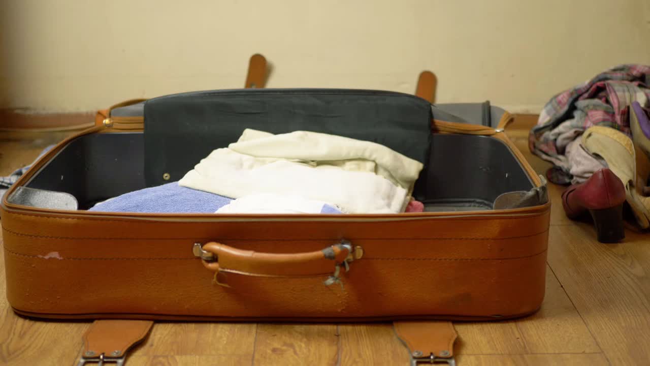 Packing old brown suitcase with clothes wide shot timelapse