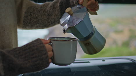 woman hands pouring espresso in cup enjoying morning at motorhome close up.