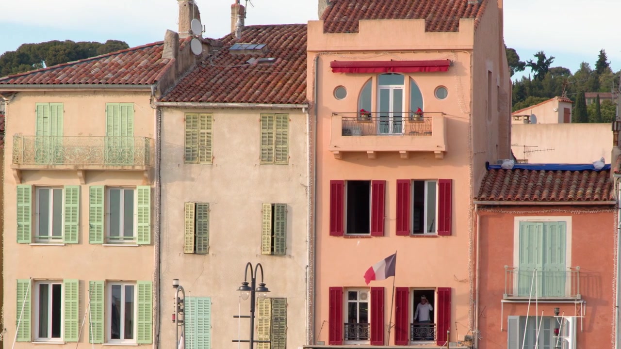 Panoramique horizontal de la caméra sur des façades méditerranéennes pastel avec des volets colorés sous une lumière du jour éclatante