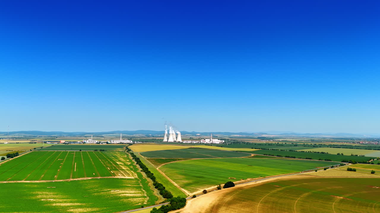 Wide pipes of the power plant produce white smoke. Enterprise works in the countryside. Aerial view