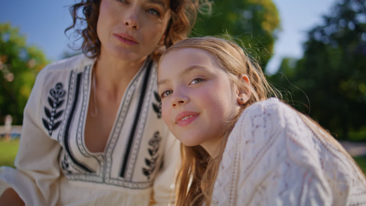 Summer mother daughter looking distance on grass closeup. Woman bonding girl