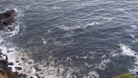 waves crashing against the black cliffs on the seaside of isle of skye, highlands of scotland