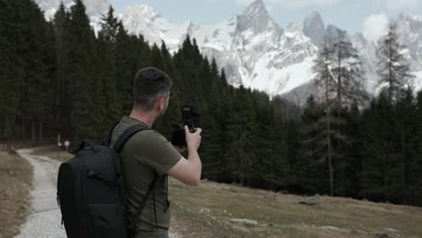 travel photographer with dslr camera capturing photo of dolomite mountains in italy