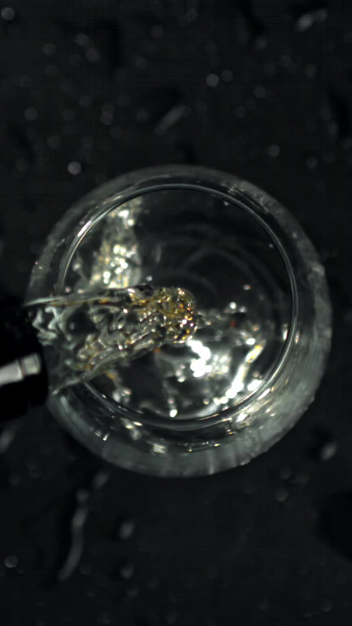 Versamento al rallentatore di liquido limpido in un bicchiere