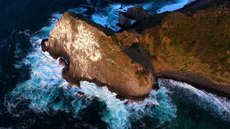 toma cinemática de drones de olas rompiendo contra una gran piedra en el agua en kyushu japón