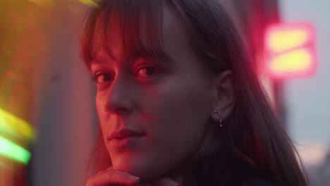young woman, girl, staring into lens, gazing, red light, blurry lights, dawn, pretty mysterious look, earring, beautiful face, cinematic close-up shot.