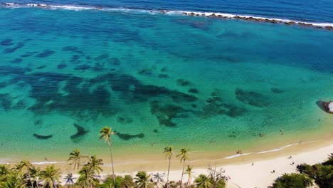 aerial view overlooking calm, turquoise ocean, palm trees and a paradise beach, in tairona national natural park, serene, sunny evening, in caribbean colombia, south america - reverse, tilt drone shot