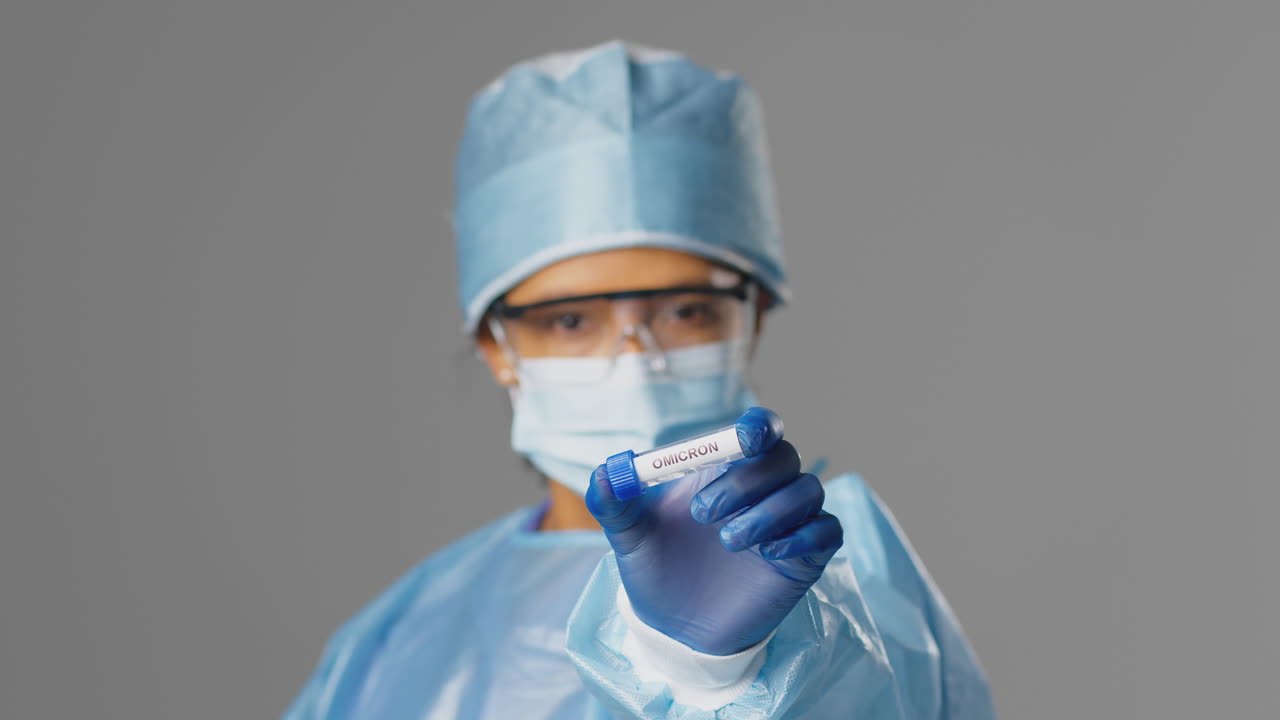 trabajadora de investigación de laboratorio con ppe sosteniendo un tubo de ensayo etiquetado con omicron