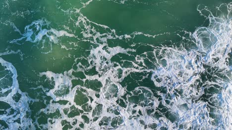 drone captures dynamic ocean waves with frothy patterns and vibrant turquoise hues under bright daylight