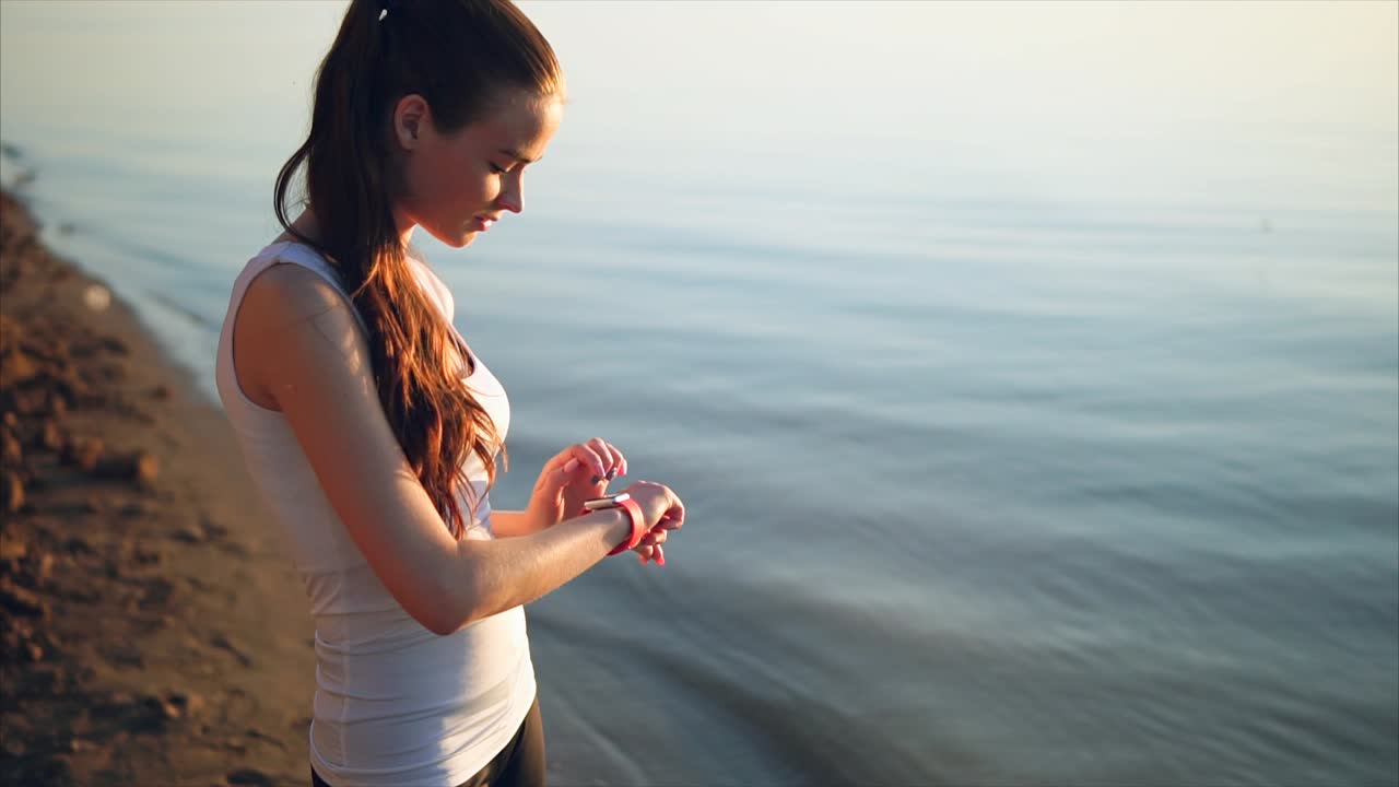 Woman Checking Smartwatch at Beach Sunset