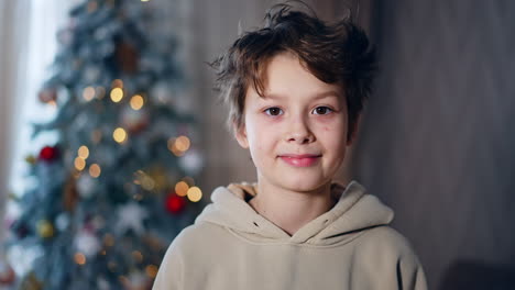 boy smiling in front of christmas tree