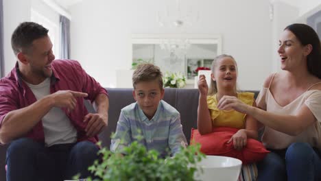 Laughing-caucasian-parents,-son-and-daughter-at-home-on-couch-watching-tv-together