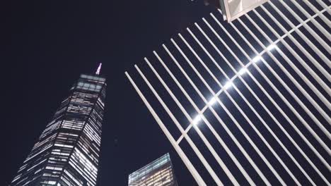 camera looking up to world trade centre oculus and skyscraper one world trade at night - streetlight passes by