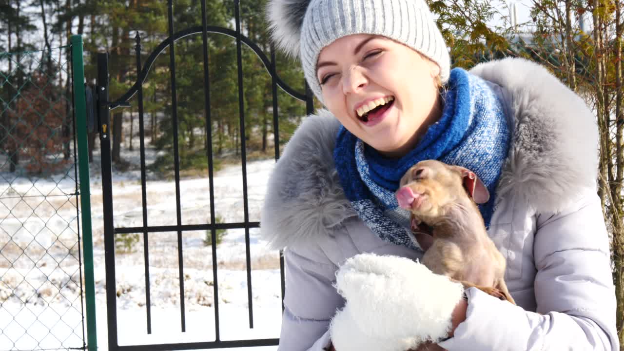여자 는 겨울 밖 에서 작은 개 와 함께 놀고 있다