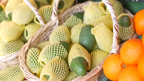 avocados and oranges in baskets at a farmers market