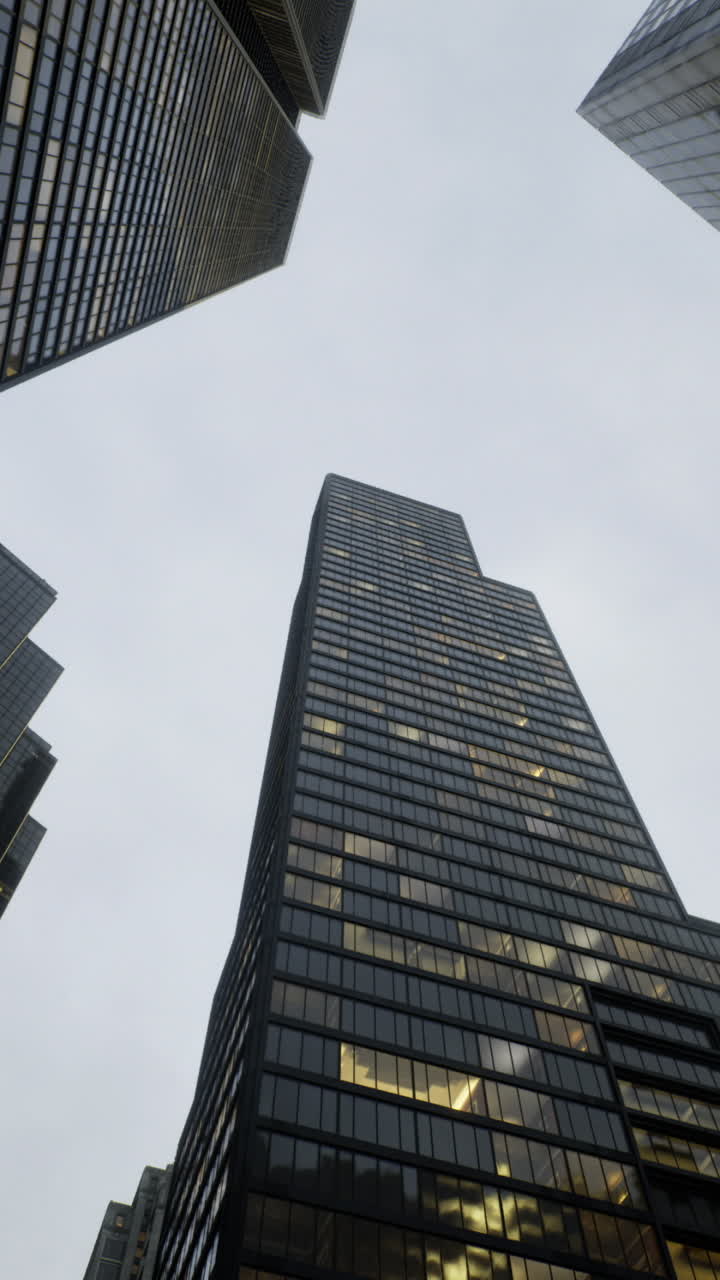 Modern skyscrapers reach toward a cloudy sky in a bustling urban landscape