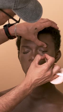 visagiste applying lipstick while doing makeup on transgender preparing for photo shoot