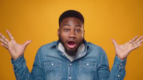 african american young man showing his mind is blown against yellow background